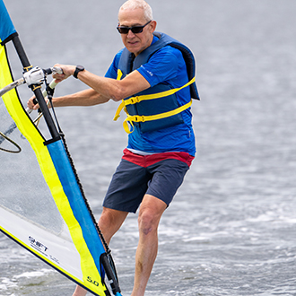 An older man windsurfing.