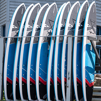 A group of paddleboards standing up-right in some racks.