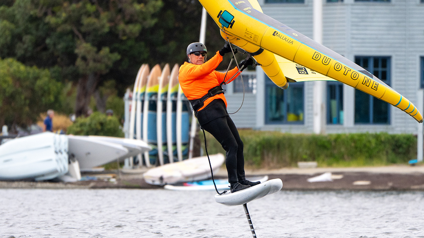 A man learing how to wingfoil on shoreline lake