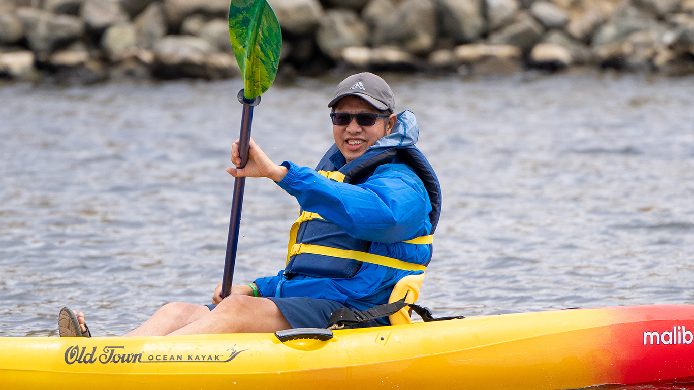 A person in a kayak on shoreline lake.