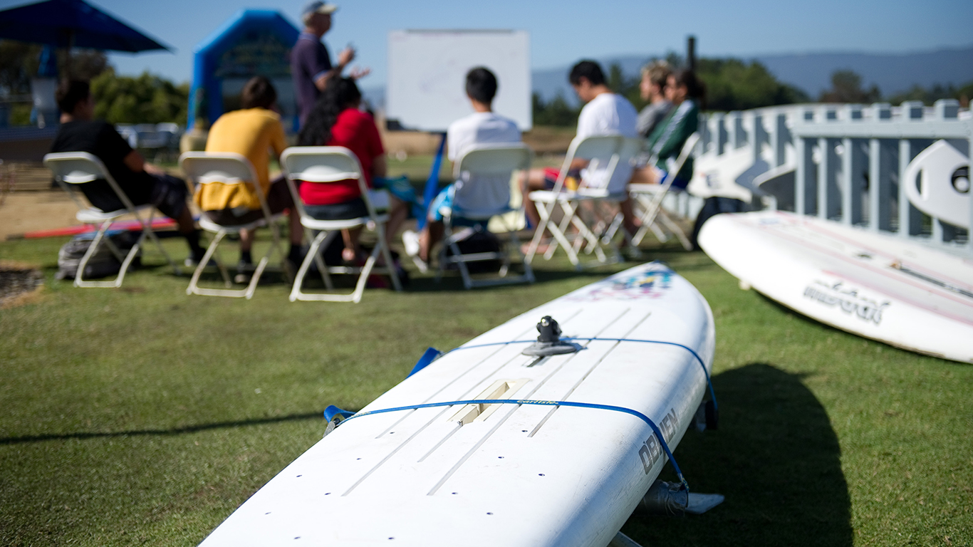 A windsurf board on the ground with a class in the back