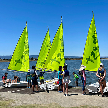A group of kids getting into sail boats.