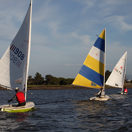 Three boats racing away on shoreline lake