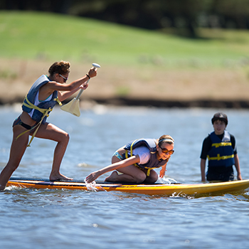 Two teens on a stand up paddleboard.