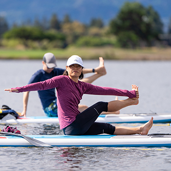 A woamn and man doing yoga on SUP baords