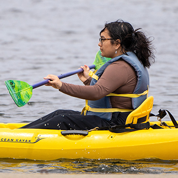A woman sailing on shoreline lake.