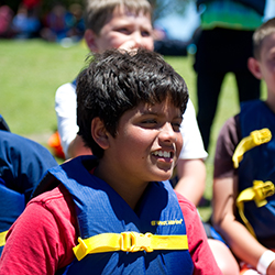 A young boy sitting on the lawn listening to instructions.